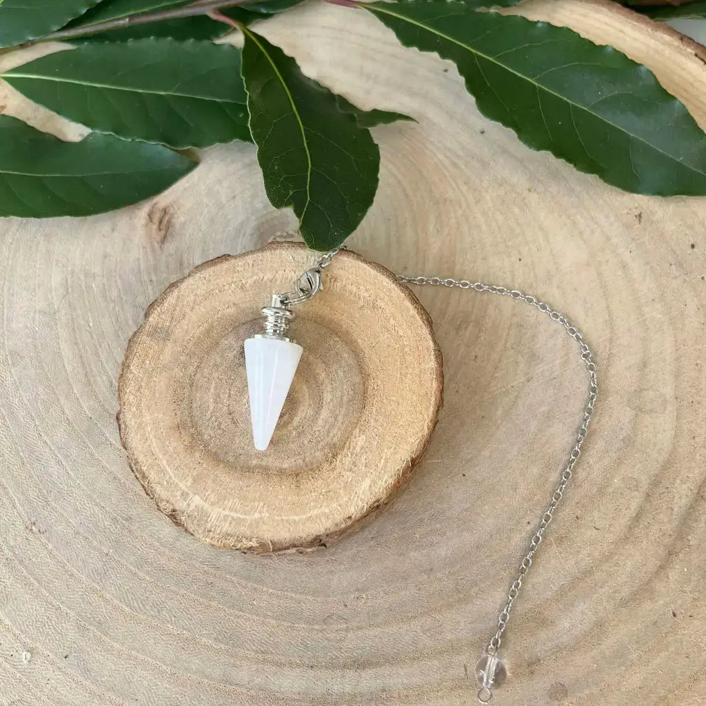 Pendule en Cristal de Roche blanc conique serti metal avec chaine sur tranche de bois et feuilles