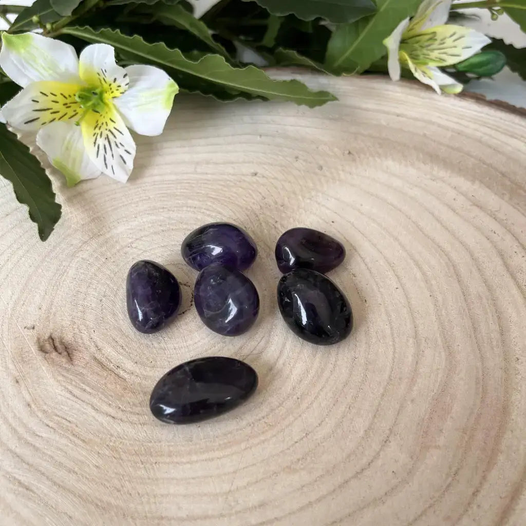 Pierre Roulée Améthyste Aura de Roche pierres polies violettes sur tranche de bois avec fleurs