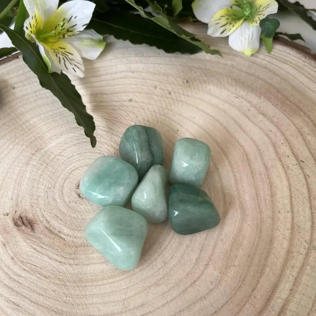 Pierre Roulée Aventurine Verte sur une planche en bois avec des fleurs en arrière-plan