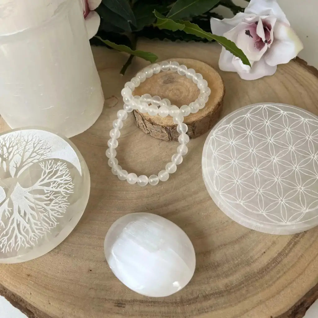 Plaque Arbre de Vie Ying et Yang en Sélénite posée sur une surface en bois avec des cristaux et décoration naturelle