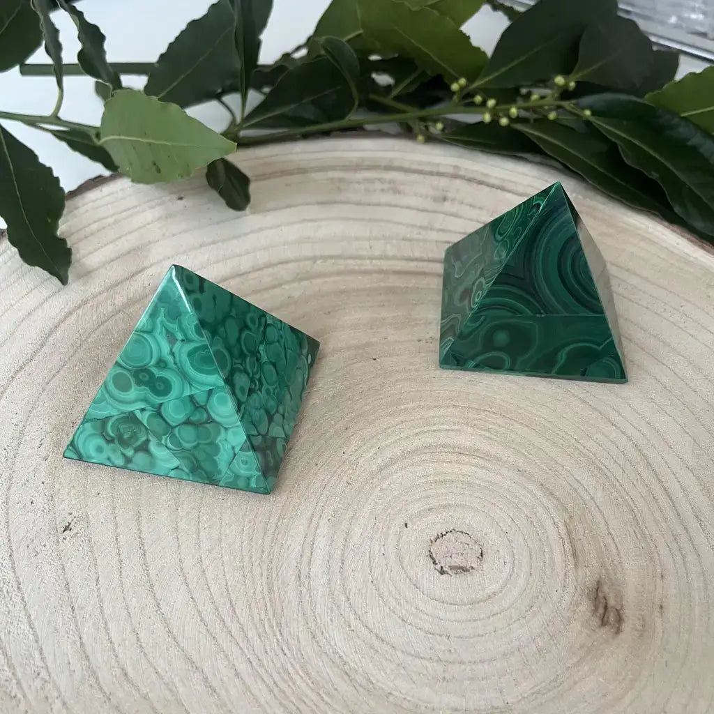 Pyramide de Malachite en pierre roulée avec des motifs verts vibrants sur un fond en bois naturel